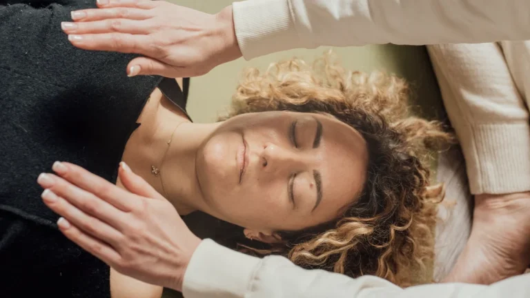 Benefícios do Reiki: para que serve e o que diz a ciência Benefícios do Reiki: terapeuta com as mãos sobre mulher deitada de olhos fechados durante sessão
